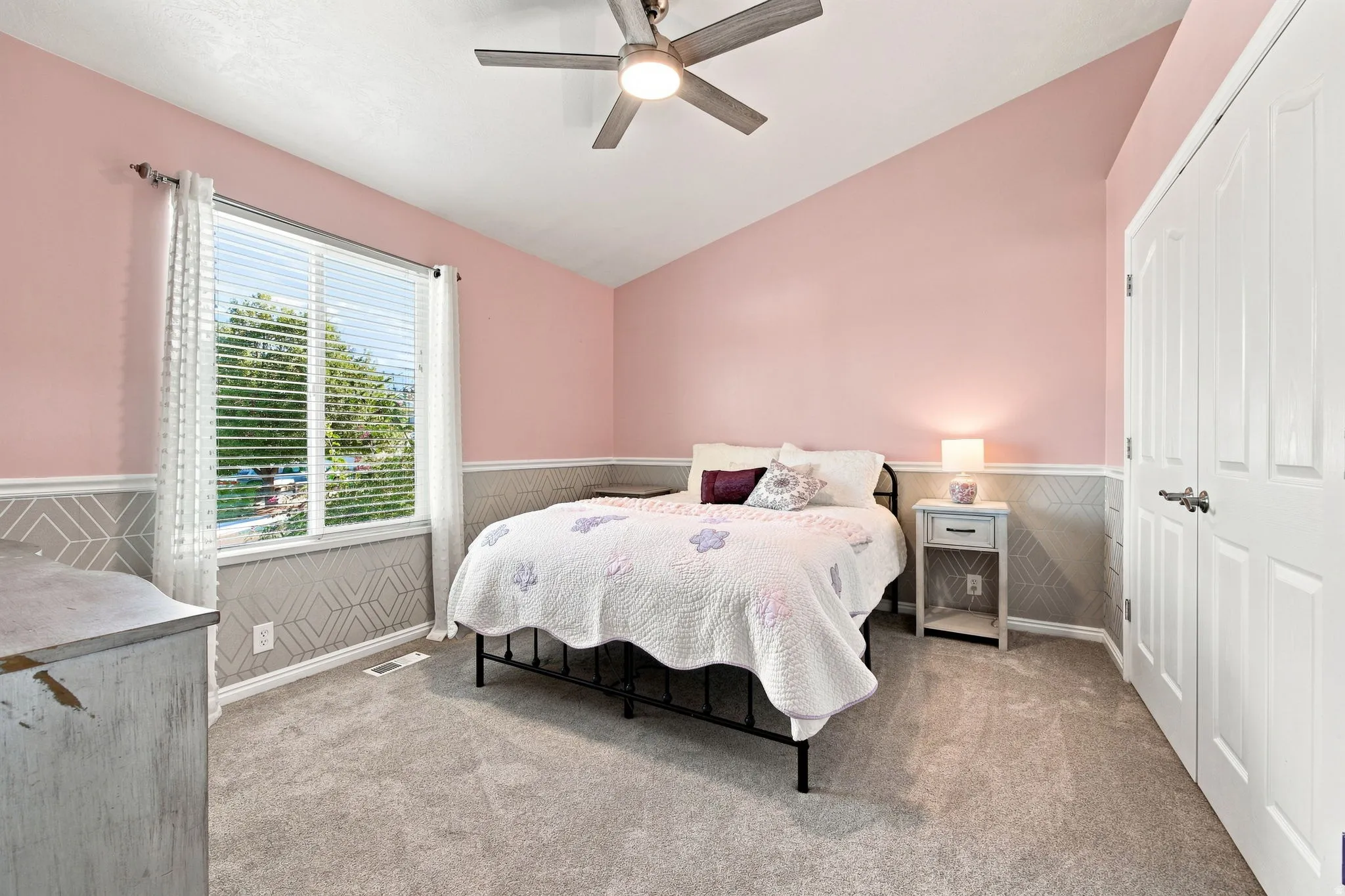 Vaulted ceiling, ceiling fan with light fixture, carpeted flooring, window with blinds, panel closet door