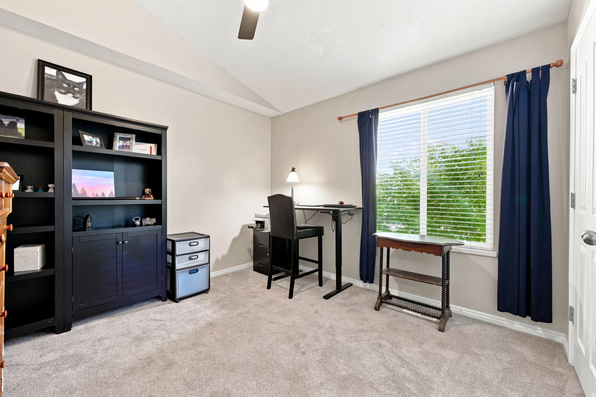 Light gray carpeting with a vaulted ceiling and a ceiling fan