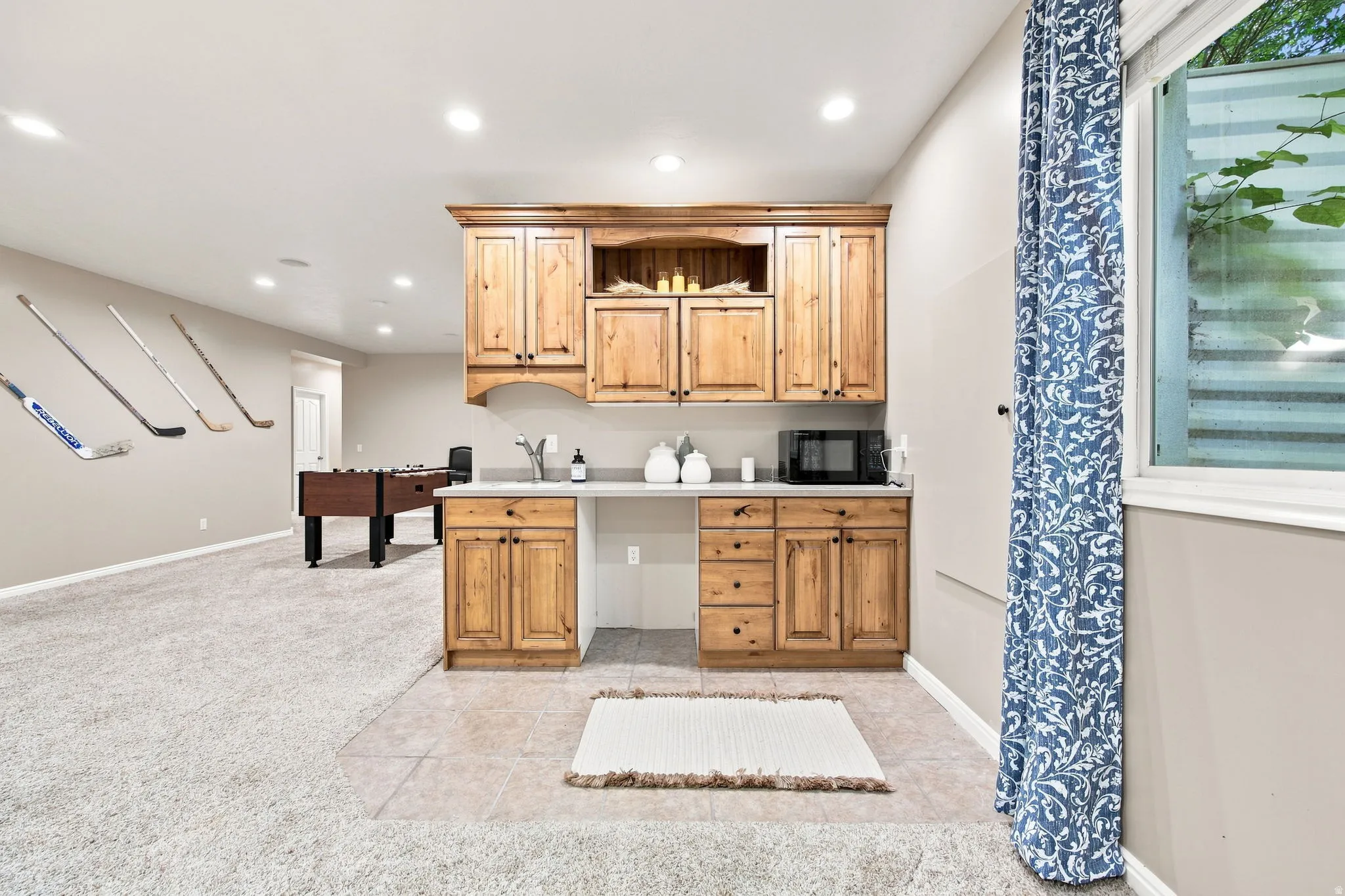 Built-in cabinetry with wood-finish doors, recessed lighting, and a window with a window well