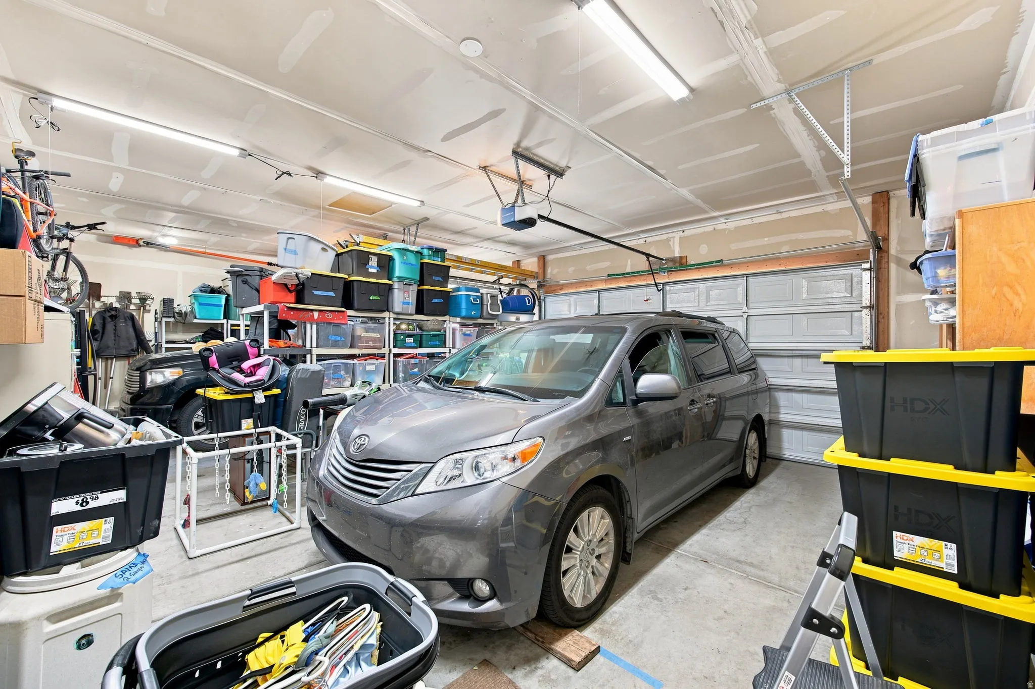 Attached two-car garage with a concrete floor, overhead lighting, and an automatic garage door opener