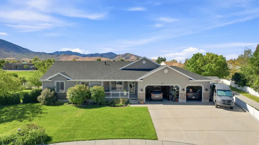 Ranch-style residence featuring a prominent two-car garage, expansive driveway, and a covered front porch with white railings