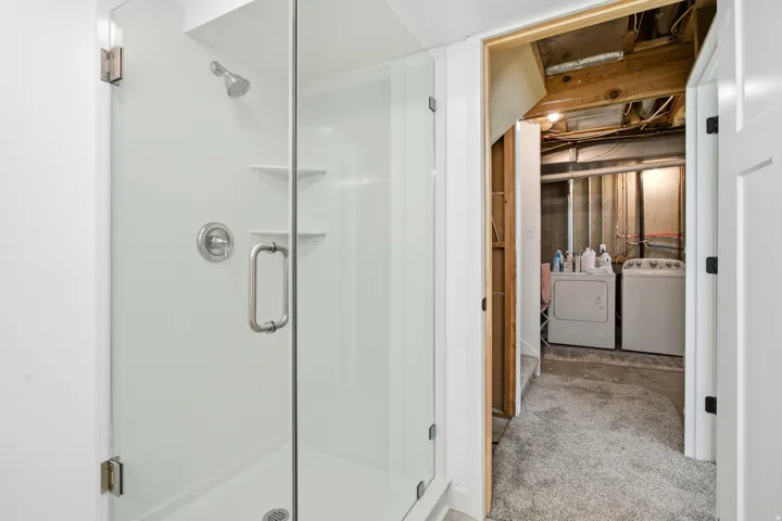 Glass-enclosed shower with a brushed nickel shower head and handle