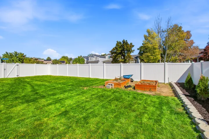 Expansive lawn area with a perimeter white vinyl fence, offering privacy