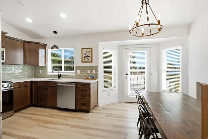 L-shaped kitchen with wood-finish cabinetry, light-toned countertops, and a subway tile backsplash
