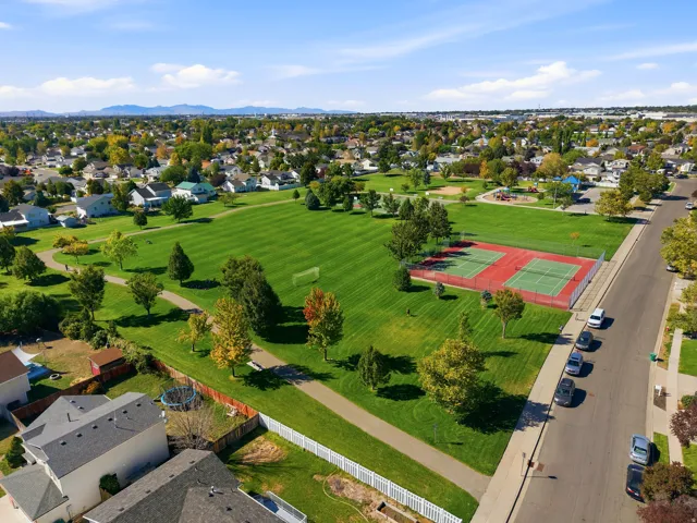 Expansive green space featuring mature trees, paved pathways, and multiple tennis courts