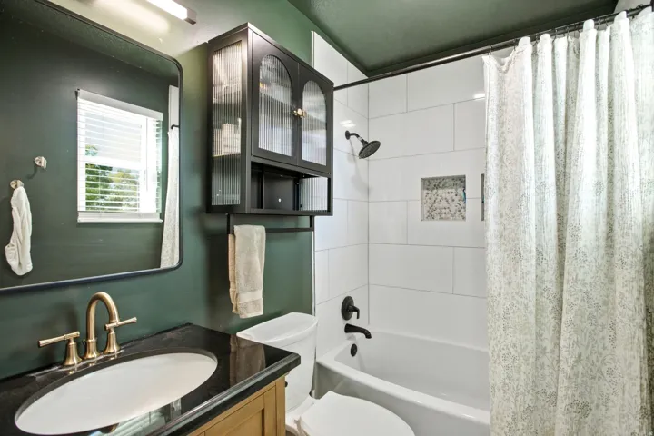 Bathroom featuring a vanity with an undermount sink, a dark countertop, and a brass-finish faucet