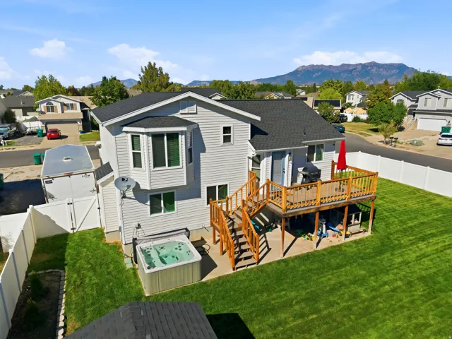 Rear exterior with multi-level wood deck, ground-level patio, and a built-in spa