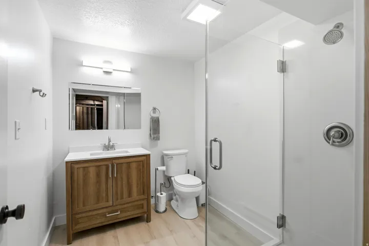 Wood-finish vanity with a white countertop, chrome faucet, and rectangular mirror