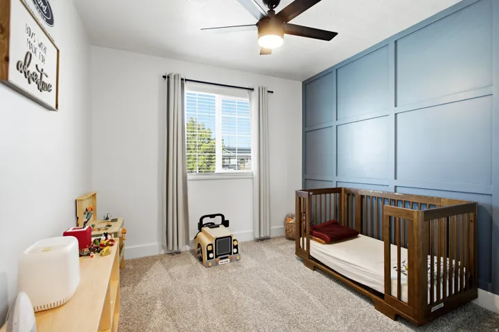 Room featuring a textured accent wall, light-colored carpeting, and a window with blinds