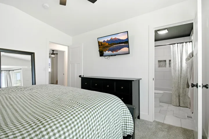 Recessed lighting illuminates a well-appointed bedroom with light-colored carpet flooring
