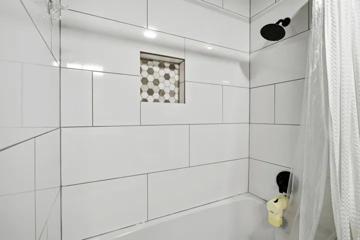 White subway tile surround with a built-in niche featuring hexagonal mosaic tile
