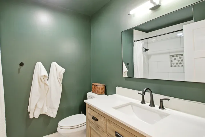 Wood-finish vanity with drawer storage, white countertop with integrated sink, and a matte black faucet