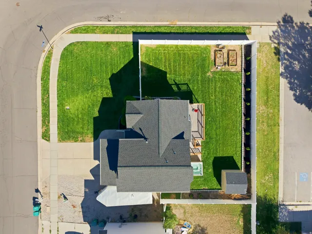 Corner lot featuring a well-maintained lawn, privacy fencing, a wood deck, a hot tub, and a storage shed