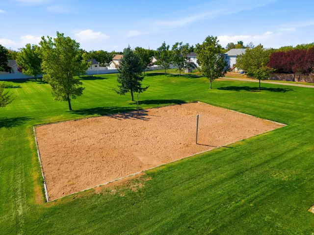 Sand court with a single net post set within a grassy expanse