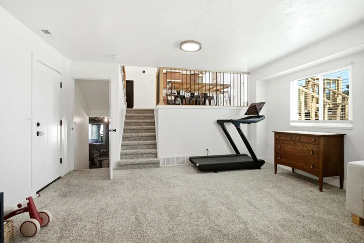 Carpeted flooring, recessed lighting, white interior doors, a window with blinds, and an open stairwell with a wood railing