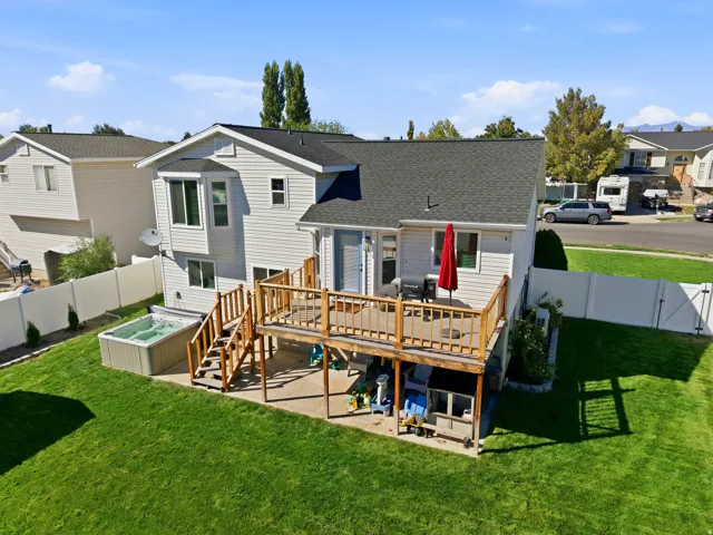Expansive backyard with a manicured lawn, full privacy fencing, and an elevated wood deck