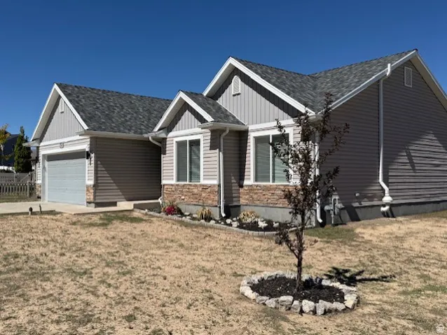 Exterior featuring horizontal siding, stone veneer accents, an attached garage, and a gabled roofline