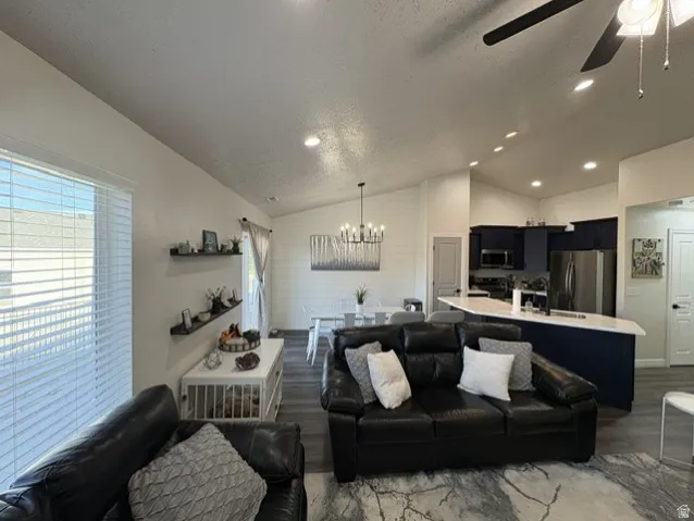 Vaulted ceilings, recessed lighting, wood-finish flooring, dark cabinetry, and stainless steel appliances