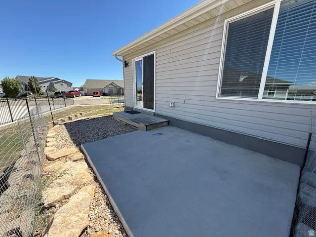 Concrete patio with a wood step, featuring a sliding glass door and an exterior light fixture