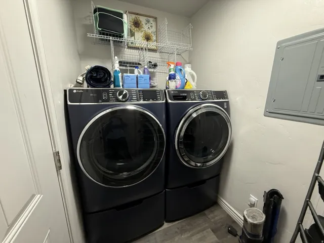 Compact laundry area with wood-finish flooring and integrated wire shelving