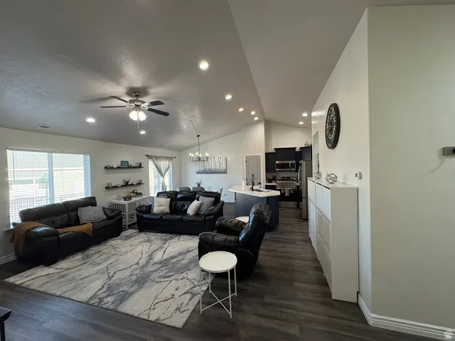 Vaulted ceilings, recessed lighting, wood-finish flooring, kitchen island with built-in sink, and shaker-style cabinetry