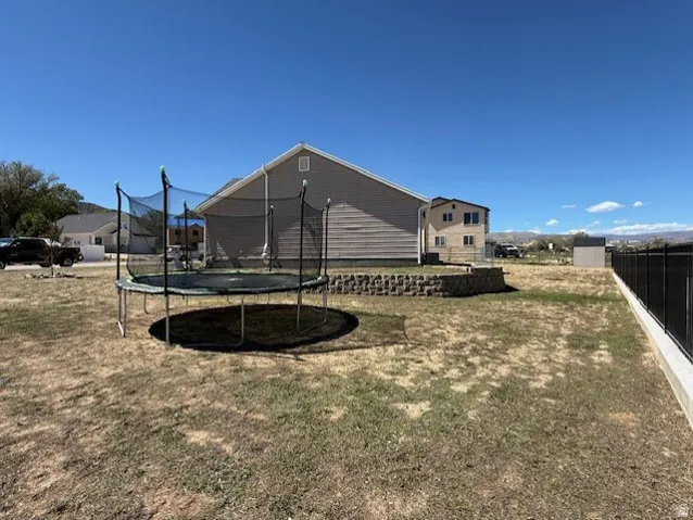 Expansive yard featuring a retaining wall, a multi-level structure, a storage shed, and perimeter fencing