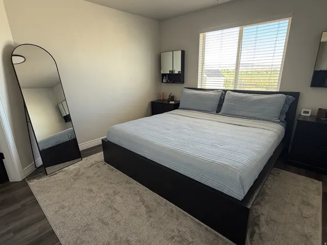 Wood-finish flooring, ample natural light from a large window, and light-toned wall finishes