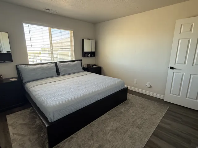 Wood-finish flooring, white paneled door with black hardware, and a window with blinds