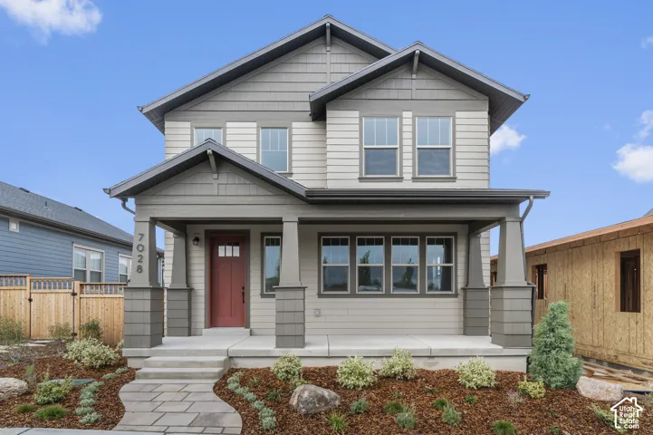 Two-story exterior featuring multi-toned horizontal lap siding, a covered front porch with tapered columns, and a flagstone walkway