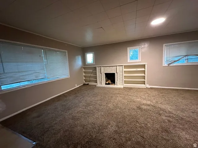 Brick-surround fireplace with built-in shelving, recessed ceiling lighting, and wall-mounted windows
