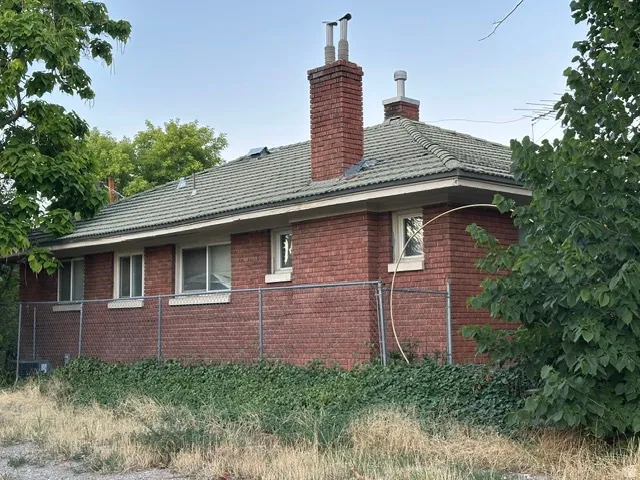 Brick exterior with a tiled roof, two brick chimneys, and multiple windows