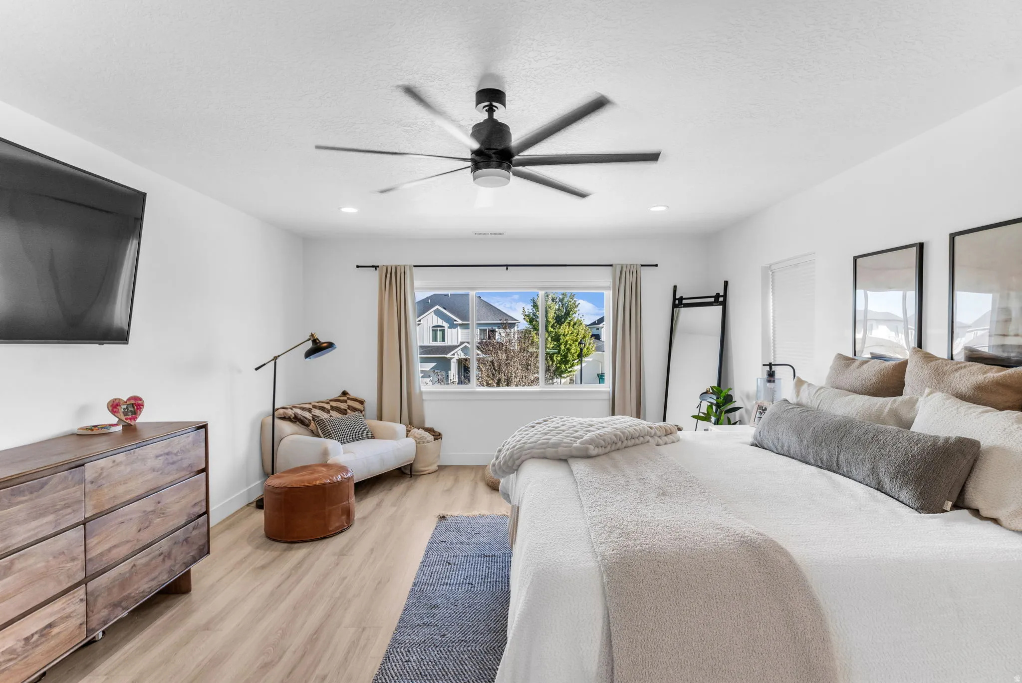 Recessed lighting, wood-finish flooring, ceiling fan, and window with neutral drapery