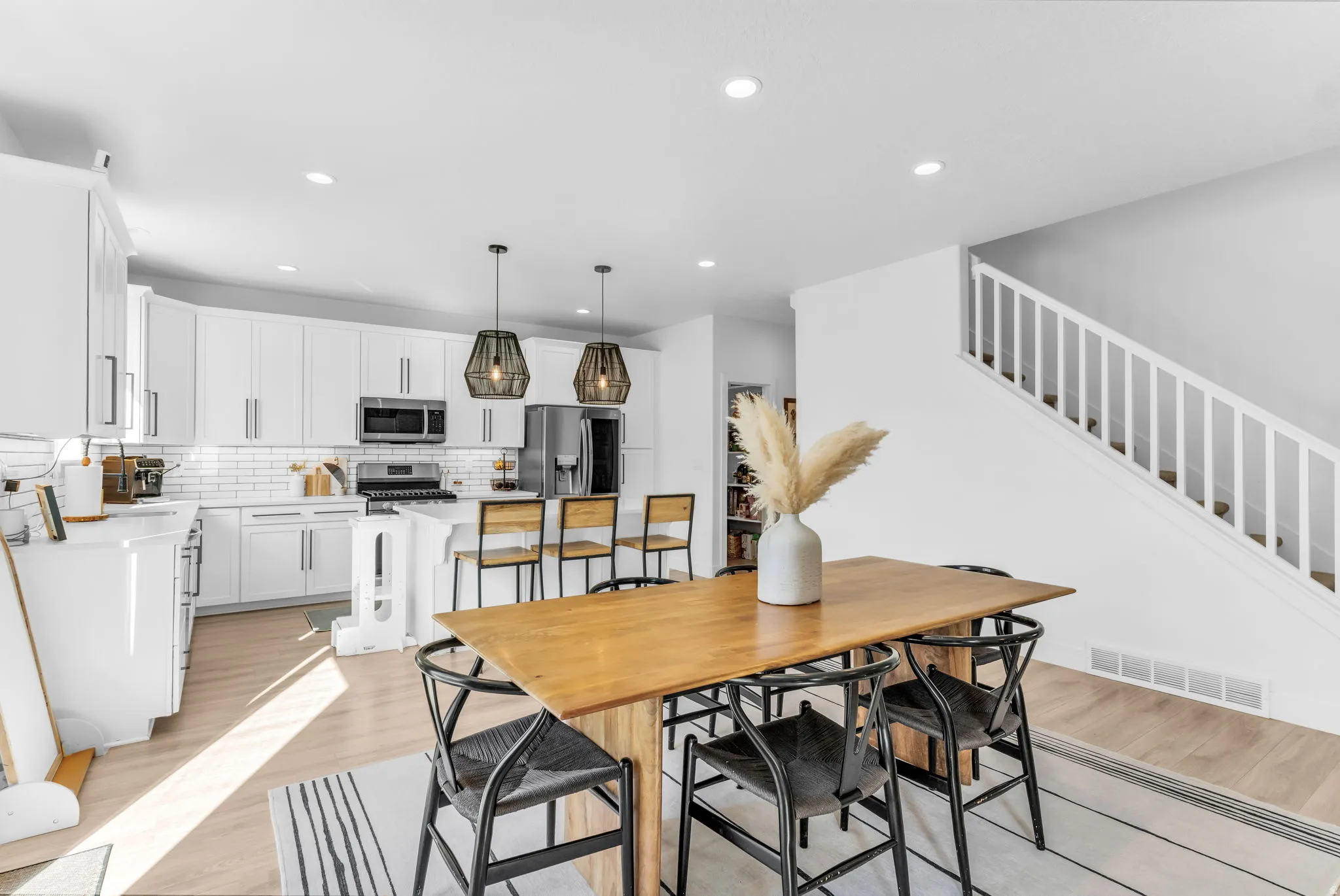Open-concept kitchen with white cabinetry, subway tile backsplash, and stainless steel appliances