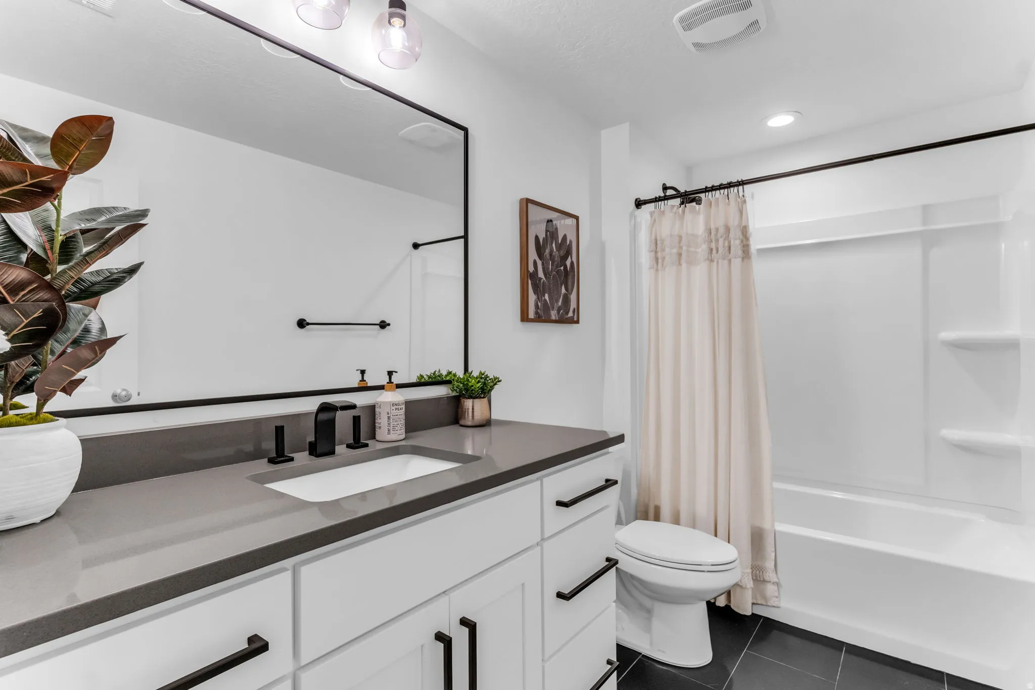 White vanity with a gray countertop, an integrated sink, and black fixtures