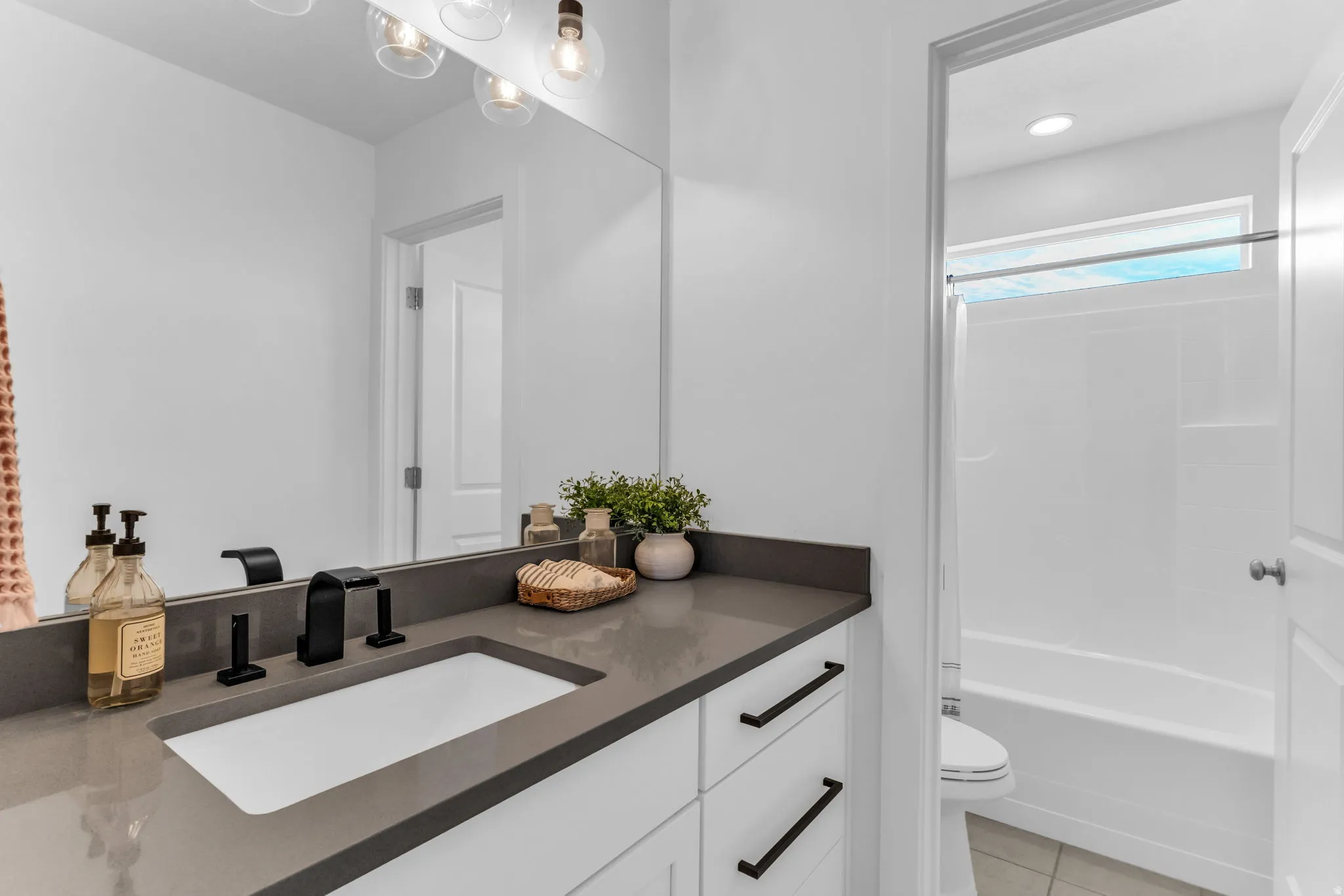 White vanity cabinetry with a dark countertop and integrated sink