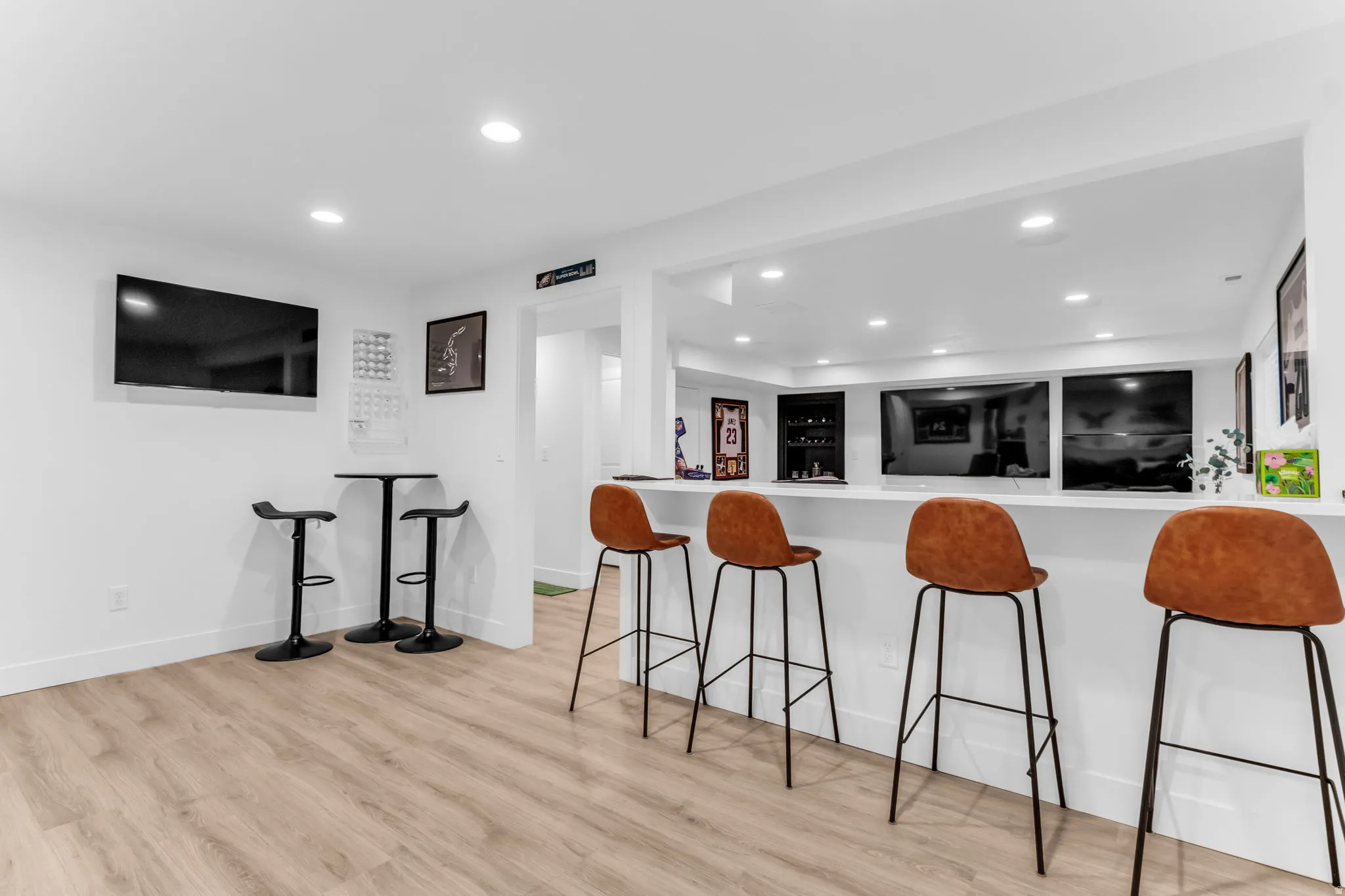 Entertainment area with light wood-finish flooring, recessed lighting, and a white countertop bar