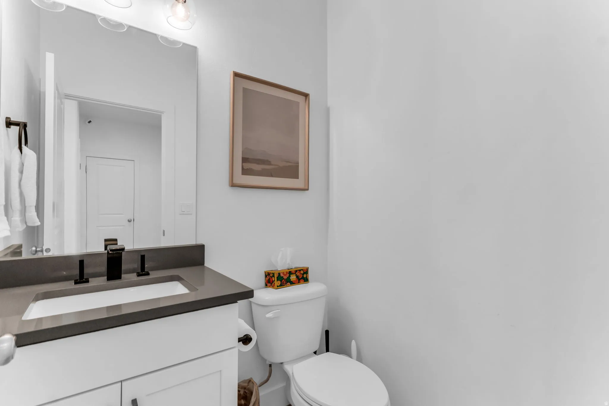 White vanity with shaker-style door, dark countertop, and matte black faucet