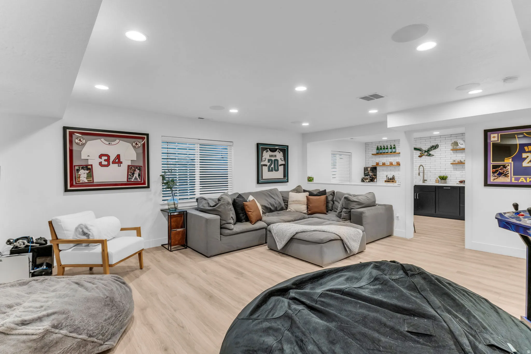 Recessed lighting, wood-finish flooring, and built-in wet bar with a white subway tile backsplash, dark cabinetry, and open shelving