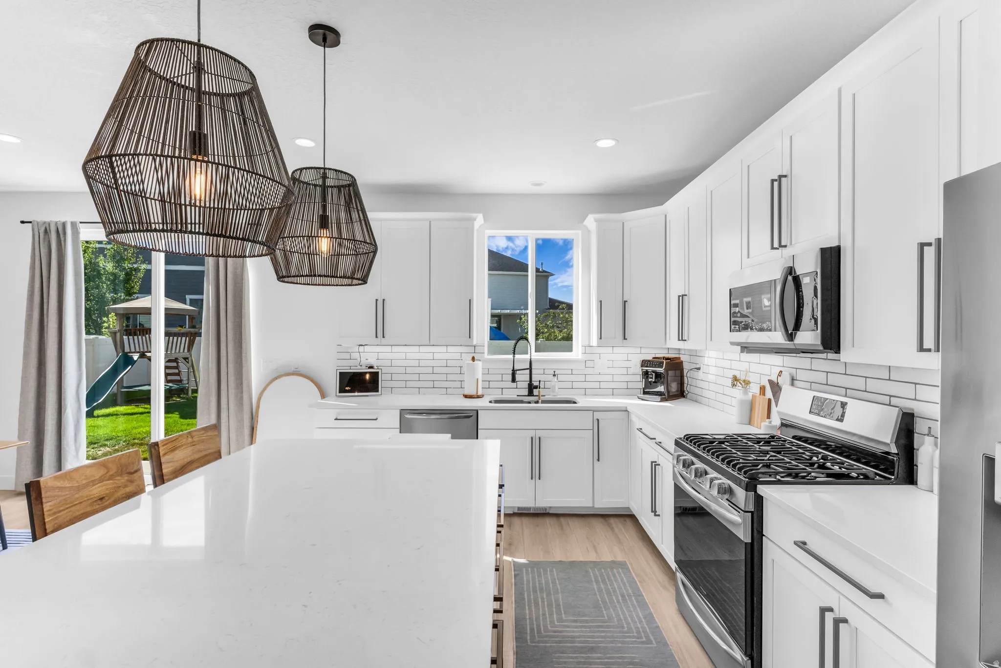 Kitchen featuring white shaker cabinetry, white subway tile backsplash, stainless steel appliances, and a central island with a solid surface countertop