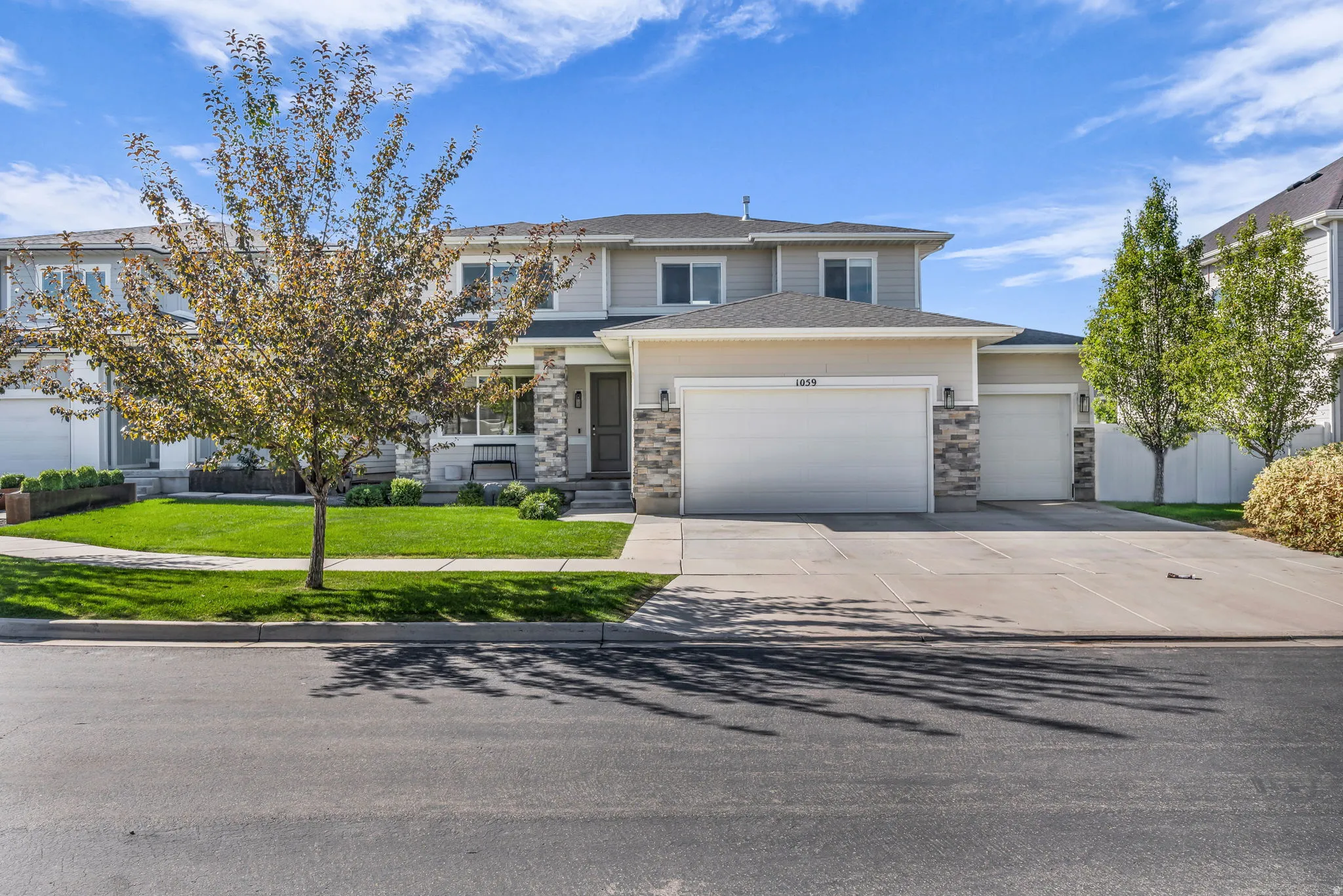 Exterior featuring a two-car garage, an additional single-car garage, stone accents, and a paved driveway