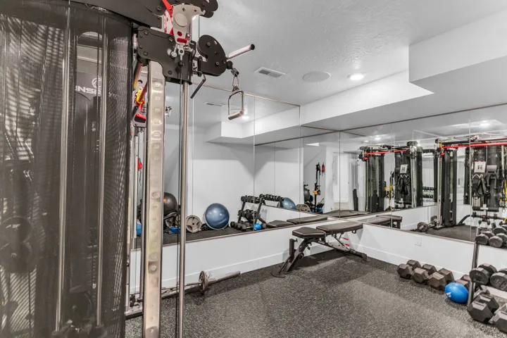 Dedicated fitness space featuring full-wall mirrors and recessed lighting