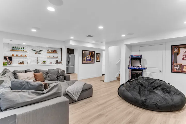 Recessed lighting, wood-finish flooring, built-in shelving, white subway tile accent wall, and a stainless steel refrigerator