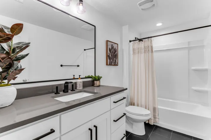 White vanity with a gray countertop, an integrated sink, and black fixtures