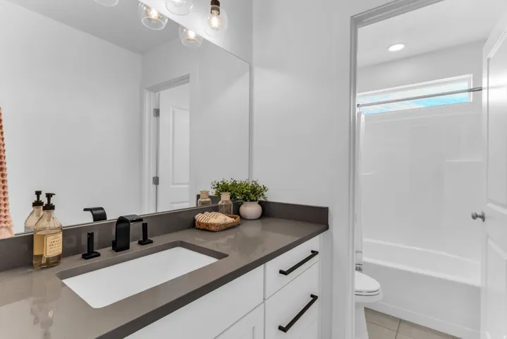 White vanity cabinetry with a dark countertop and integrated sink