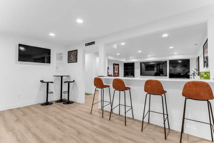 Entertainment area with light wood-finish flooring, recessed lighting, and a white countertop bar