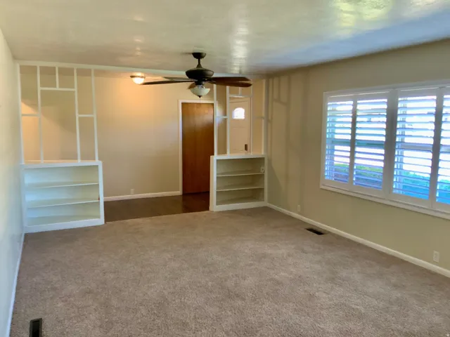 Built-in shelving units, wall-to-wall carpeting, wood-finish flooring, ceiling fan, and plantation shutters