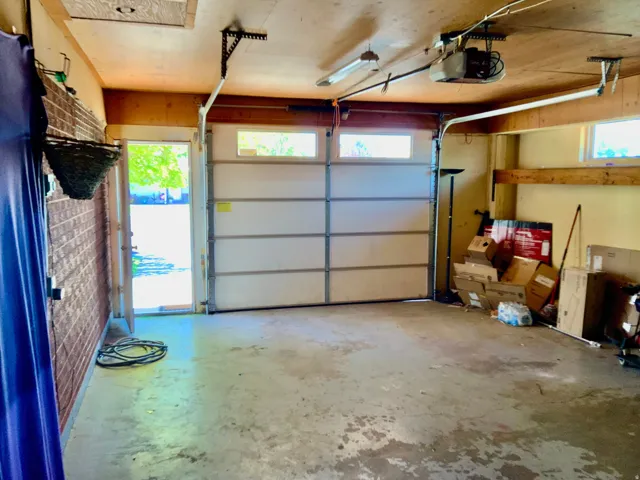 Attached garage featuring a concrete floor, overhead lighting, and an automatic garage door opener