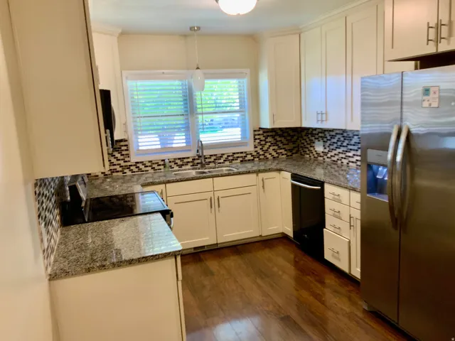 Kitchen featuring white shaker cabinetry, stainless steel appliances, speckled countertops, a mosaic tile backsplash, and wood-finish flooring