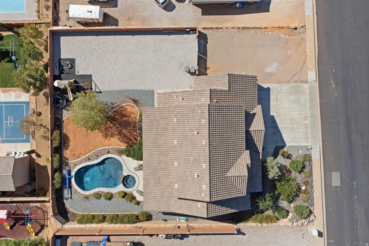 Tile roof residence featuring a backyard swimming pool, integrated spa, and desert landscaping