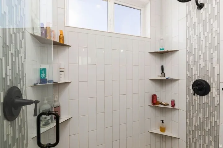 White subway tile shower surround with a decorative mosaic tile accent strip